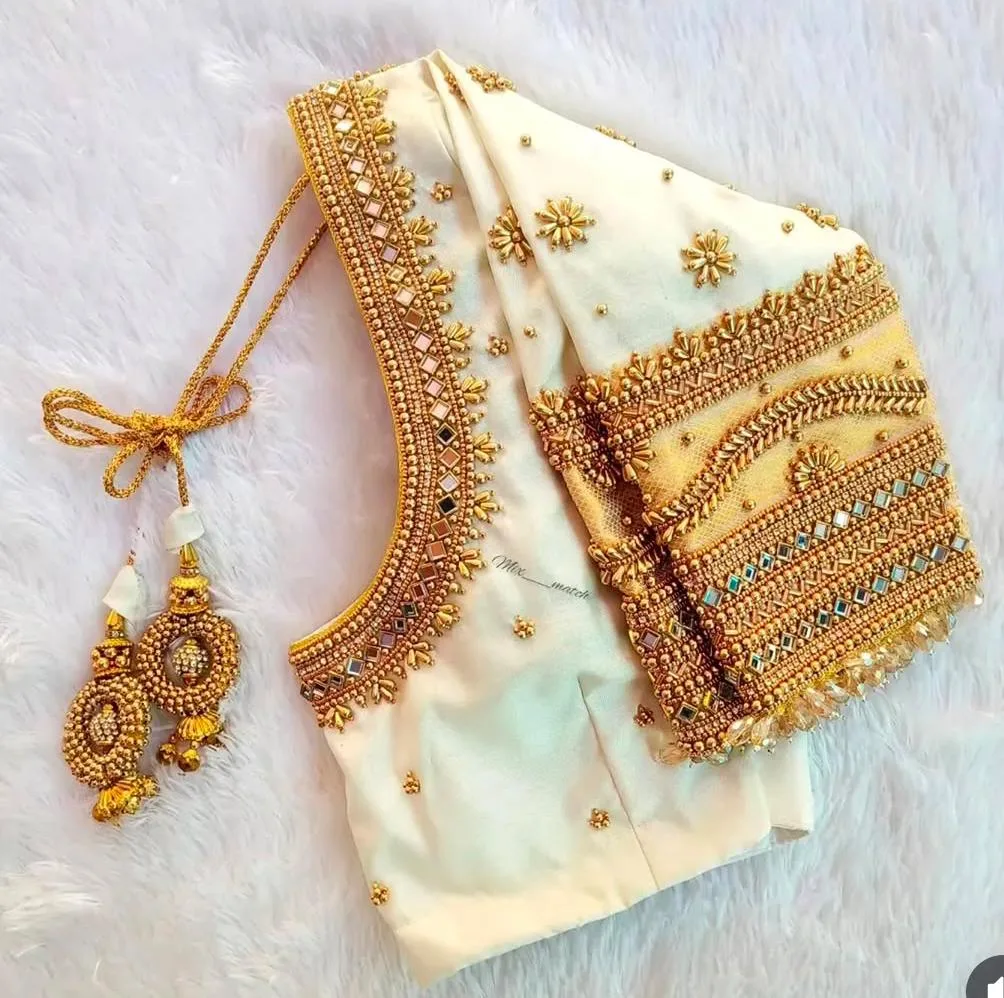 Cream blouse with detailed gold Aari embroidery and matching tassels