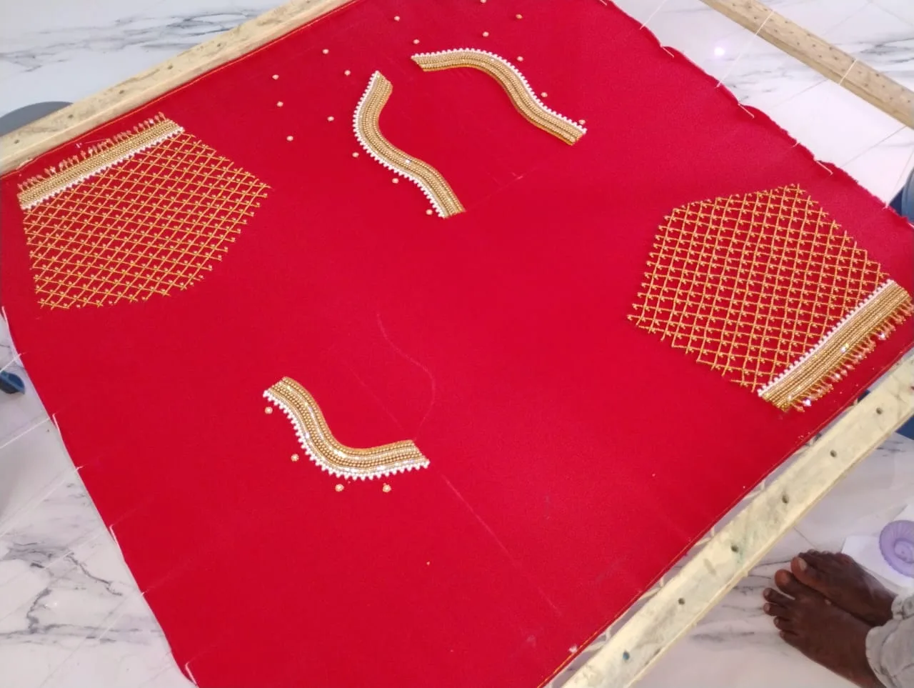 Gold Aari work arranged on bright red blouse fabric