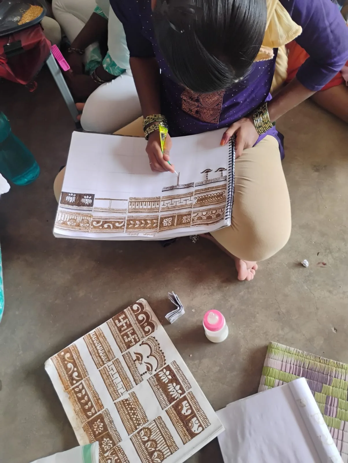 Learner practicing Mehendi border patterns in a design book